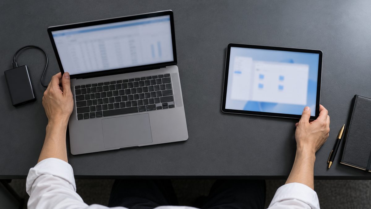 社用ノートPCとタブレットを両手で見比べる真上からの手元