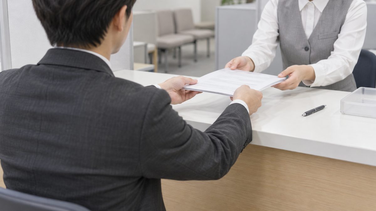 求人の受付窓口のカウンターで採用担当者が職員に求人の申込み書類を差し出す場面