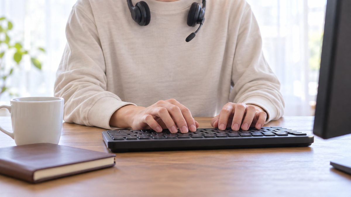 自宅の書斎で首にヘッドセットをかけた担当者がキーボードを打つ